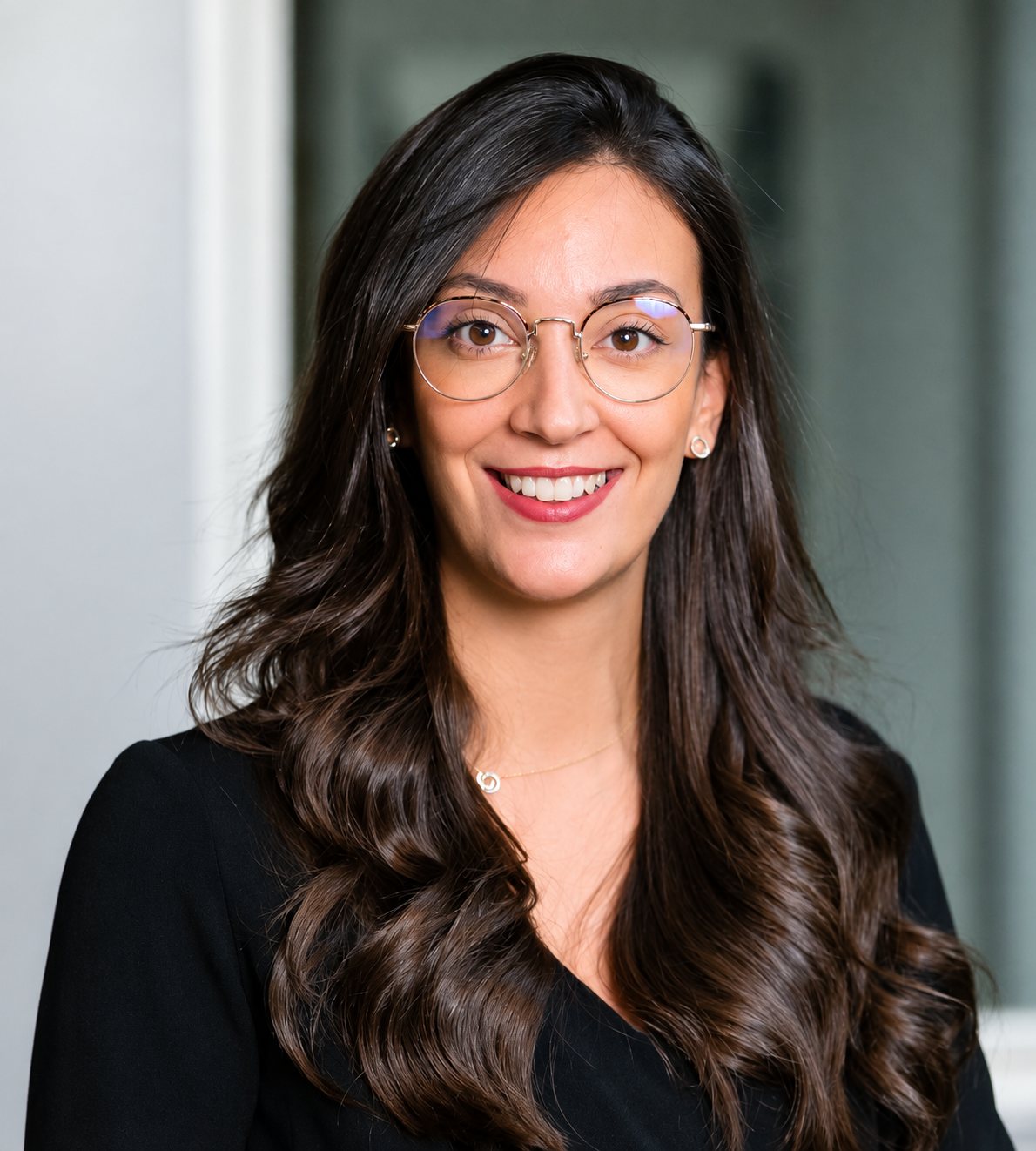 Portrait de Maïssa Labidi, souriante, lunettes rondes, cheveux longs ondulés.